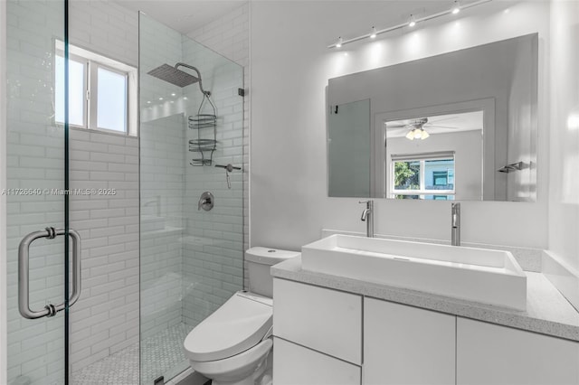 bathroom with toilet, a shower with shower door, ceiling fan, and vanity