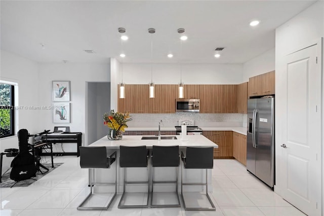 kitchen with stainless steel appliances, sink, decorative light fixtures, a kitchen bar, and tasteful backsplash