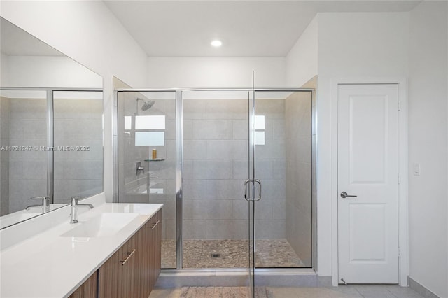 bathroom with a shower with door, vanity, and tile patterned floors