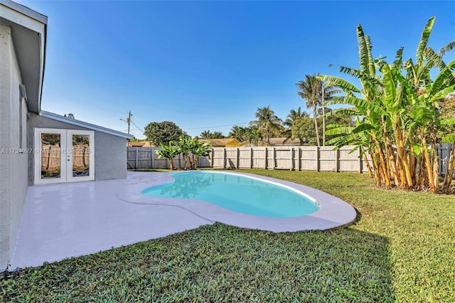 view of swimming pool with french doors, a patio area, and a lawn