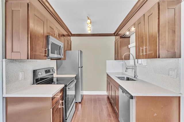 kitchen with light hardwood / wood-style flooring, tasteful backsplash, appliances with stainless steel finishes, ornamental molding, and sink