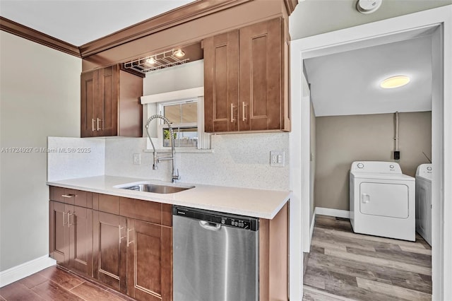 kitchen with stainless steel dishwasher, washer and clothes dryer, sink, and tasteful backsplash