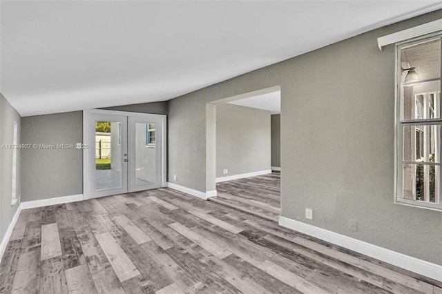 spare room featuring lofted ceiling, french doors, and wood-type flooring