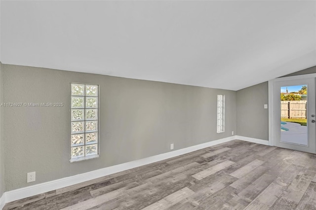 unfurnished room with lofted ceiling and light wood-type flooring