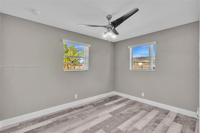 spare room with ceiling fan, a wealth of natural light, and light wood-type flooring