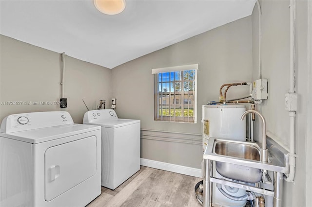 clothes washing area with sink, light hardwood / wood-style flooring, and independent washer and dryer