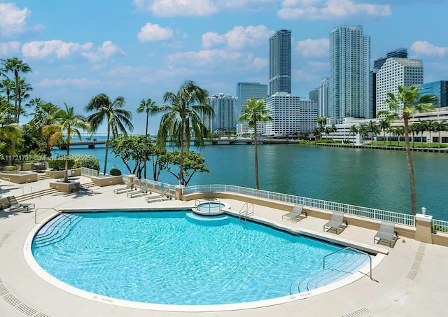 view of swimming pool featuring a patio and a water view