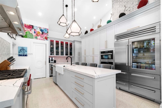 kitchen with island exhaust hood, hanging light fixtures, a spacious island, sink, and premium appliances