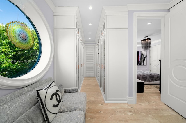 hallway with ornamental molding and light hardwood / wood-style flooring