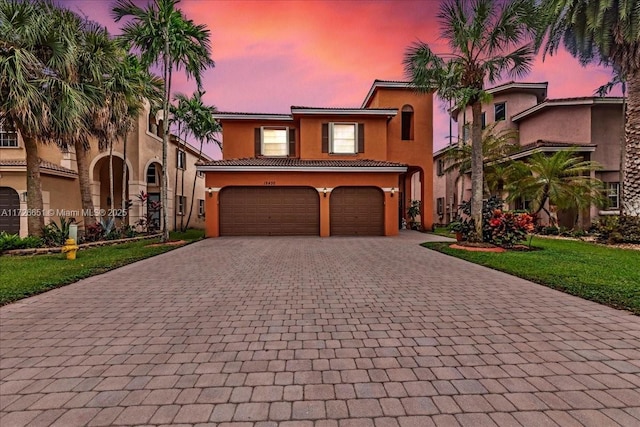 mediterranean / spanish-style house with a lawn and a garage