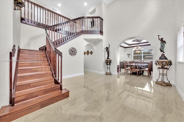 entryway with a high ceiling, a notable chandelier, and crown molding