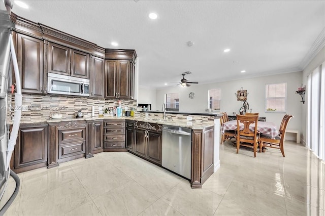 kitchen featuring stainless steel appliances, ceiling fan, kitchen peninsula, backsplash, and dark brown cabinets