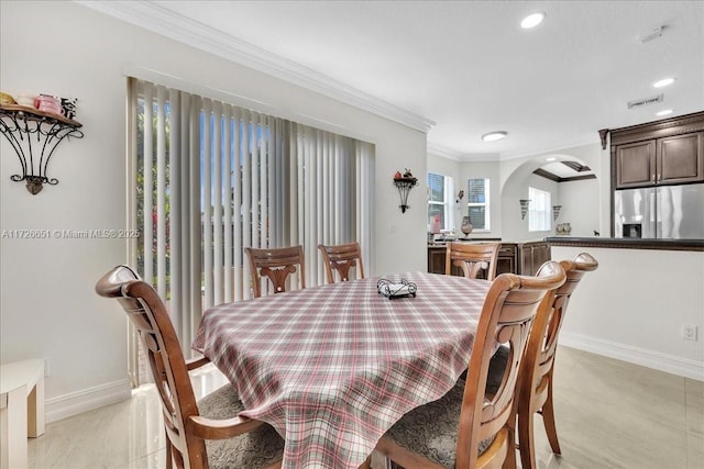 tiled dining room featuring ornamental molding and plenty of natural light