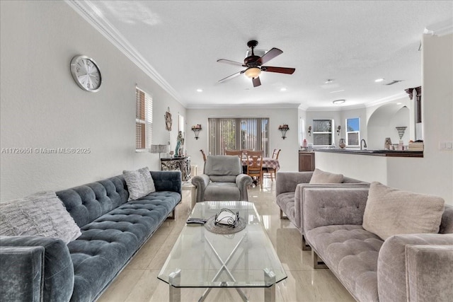 living room with sink, a textured ceiling, ceiling fan, light wood-type flooring, and crown molding