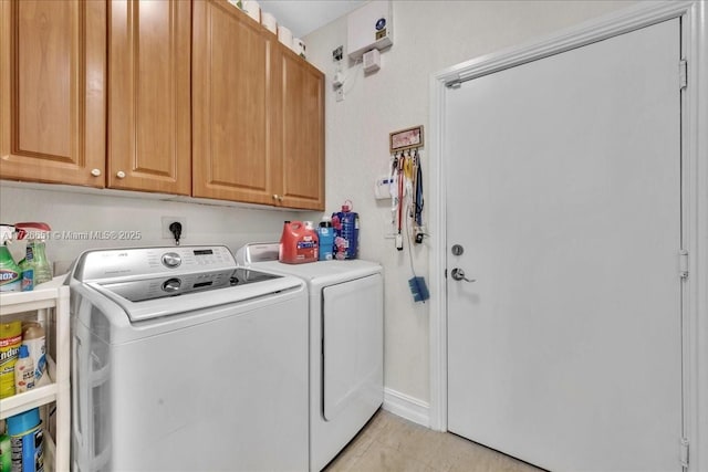 laundry area featuring cabinets, light tile patterned floors, and washer and clothes dryer