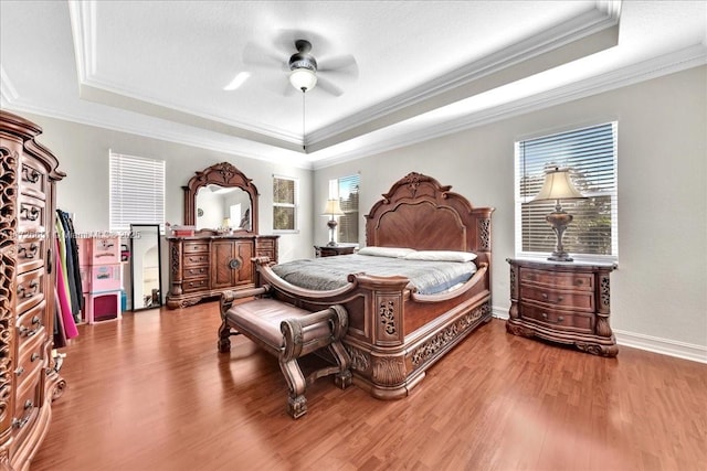 bedroom with ornamental molding, ceiling fan, a tray ceiling, and hardwood / wood-style floors