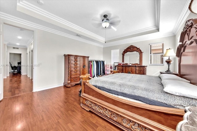 bedroom with ornamental molding, ceiling fan, and a tray ceiling