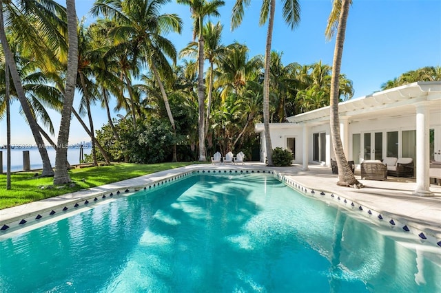 view of swimming pool with a patio area, an outdoor living space, a lawn, and a water view