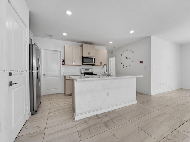 kitchen with light brown cabinetry, sink, stainless steel appliances, and a center island with sink