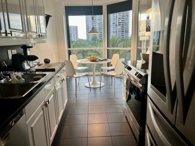 kitchen featuring sink, white cabinets, a healthy amount of sunlight, hanging light fixtures, and appliances with stainless steel finishes