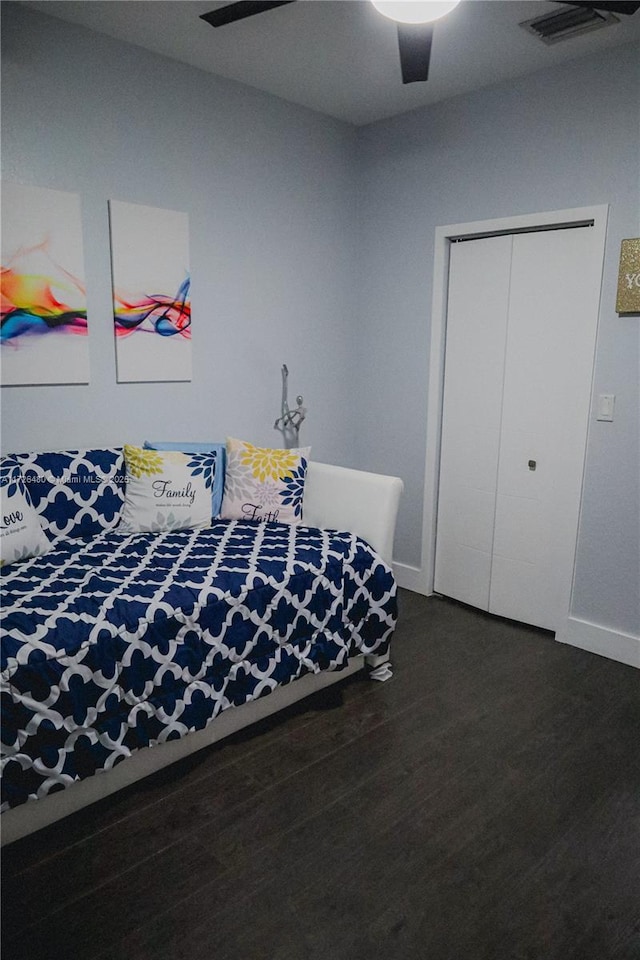 bedroom with dark wood-type flooring, ceiling fan, and a closet