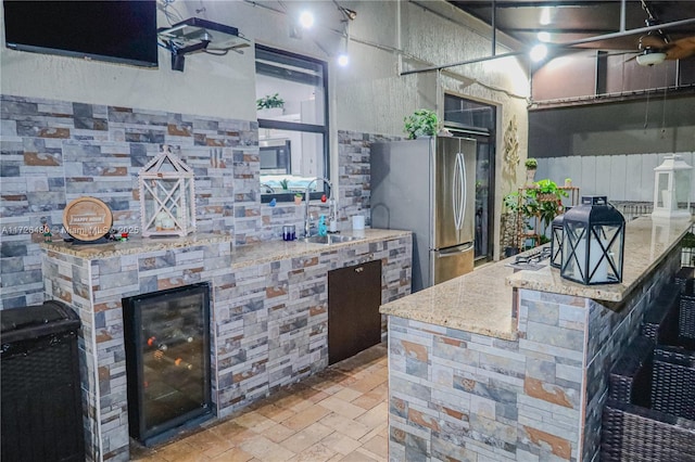 kitchen with light stone counters, stainless steel fridge, and sink