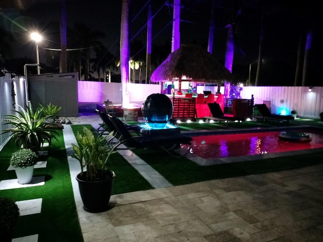 yard at twilight featuring a gazebo, a fenced in pool, and a patio area