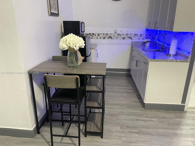 kitchen with light hardwood / wood-style floors, light stone countertops, and sink