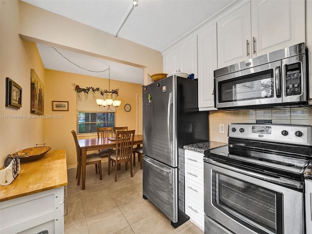 kitchen with white cabinets, decorative backsplash, hanging light fixtures, a chandelier, and appliances with stainless steel finishes