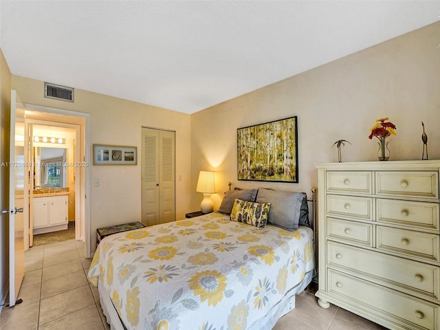 tiled bedroom with connected bathroom and a closet