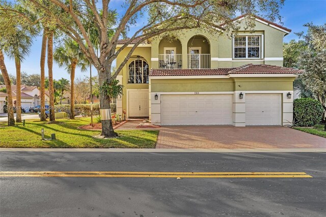 mediterranean / spanish house with a balcony, a garage, and a front lawn