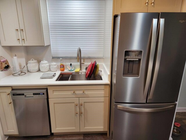 kitchen with stainless steel appliances, cream cabinets, and sink