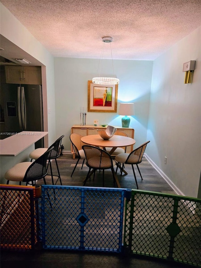 dining space featuring baseboards, wood finished floors, and a textured ceiling
