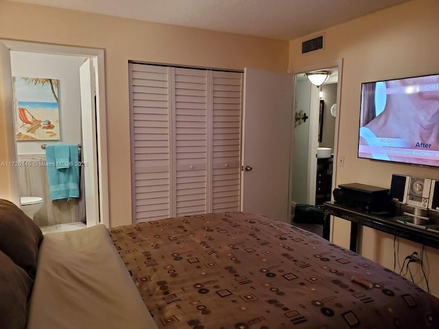 bedroom with ensuite bath, visible vents, and a closet