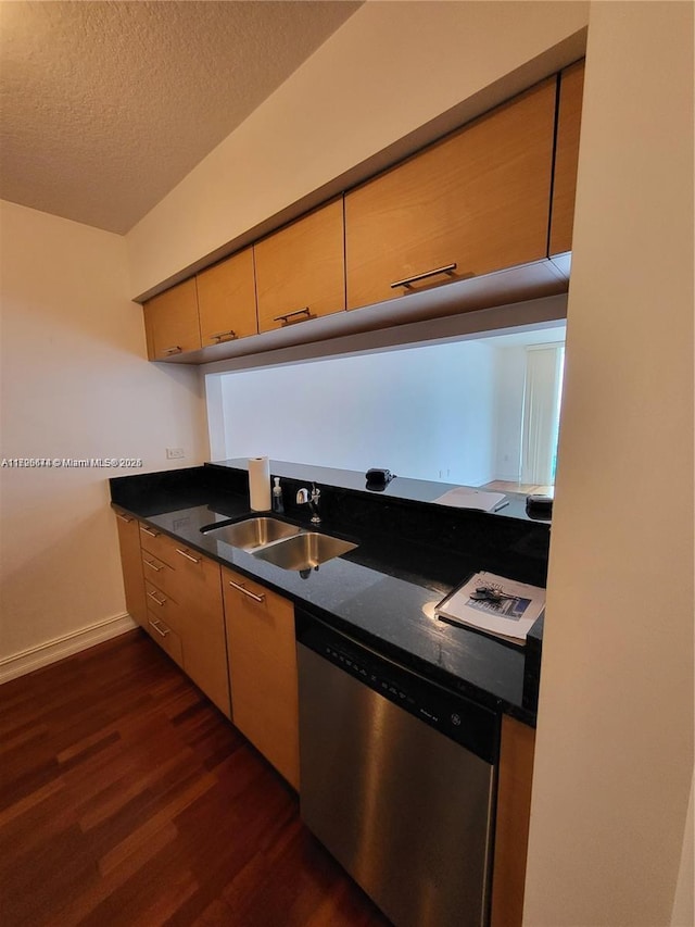 kitchen with a textured ceiling, stainless steel dishwasher, dark hardwood / wood-style floors, and sink