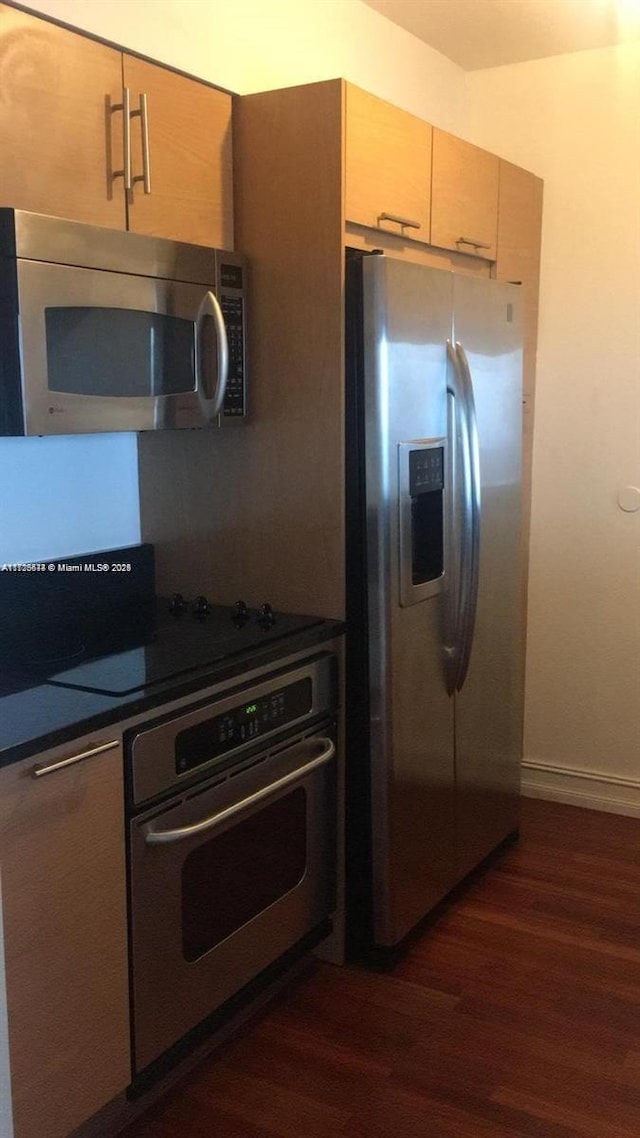 kitchen featuring light brown cabinetry, dark hardwood / wood-style flooring, and stainless steel appliances