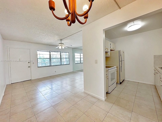 kitchen featuring white appliances, white cabinets, light tile patterned flooring, and ceiling fan with notable chandelier