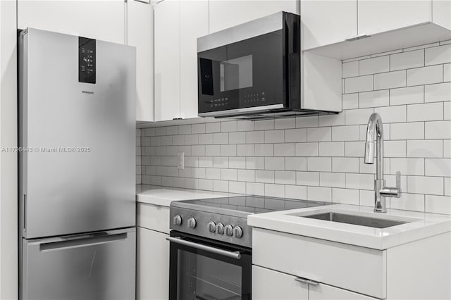 kitchen featuring stainless steel appliances, white cabinets, and tasteful backsplash