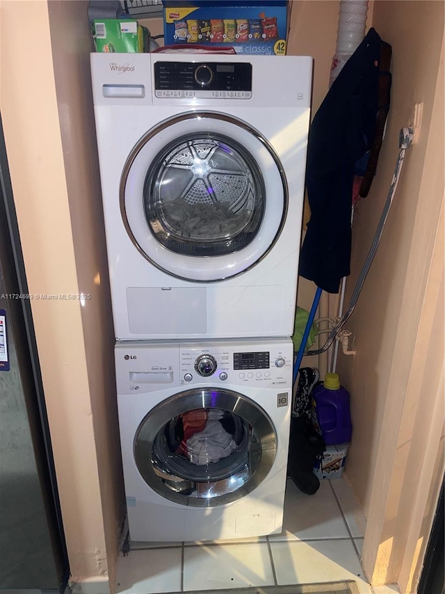 laundry room featuring stacked washing maching and dryer and tile patterned floors