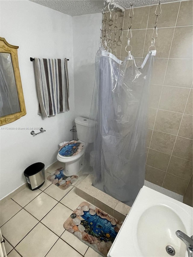 bathroom featuring toilet, vanity, tile patterned flooring, a textured ceiling, and curtained shower