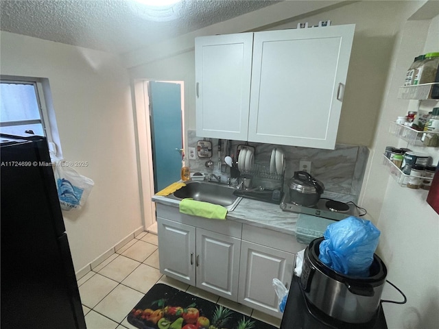 kitchen with light tile patterned floors, white cabinets, sink, and tasteful backsplash