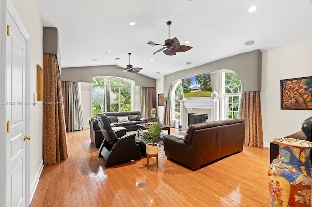 living room with light hardwood / wood-style floors, ceiling fan, and lofted ceiling