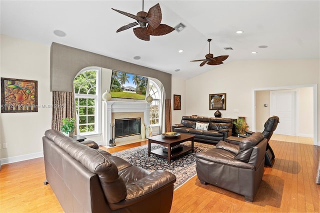 living room with lofted ceiling, a fireplace, ceiling fan, and light hardwood / wood-style floors