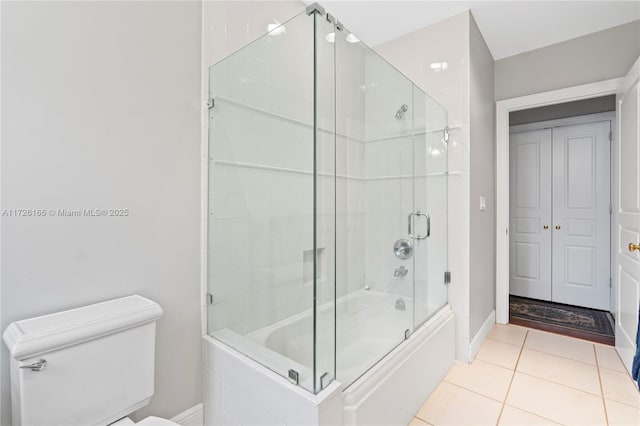 bathroom featuring toilet, tile patterned flooring, and bath / shower combo with glass door