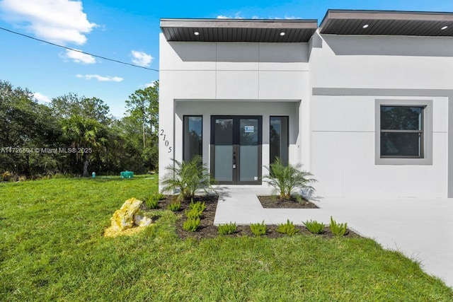 back of house featuring french doors and a lawn