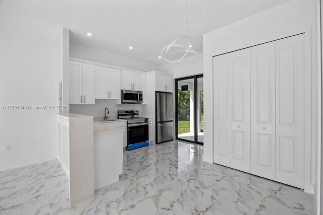 kitchen featuring sink, appliances with stainless steel finishes, white cabinetry, hanging light fixtures, and a chandelier