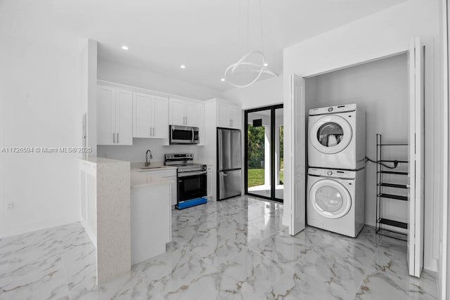 kitchen featuring sink, appliances with stainless steel finishes, stacked washer / drying machine, white cabinets, and decorative light fixtures