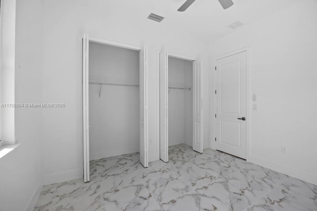 unfurnished bedroom with ceiling fan and multiple closets