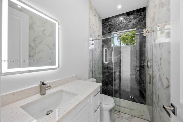 bathroom featuring a shower with door, vanity, and toilet