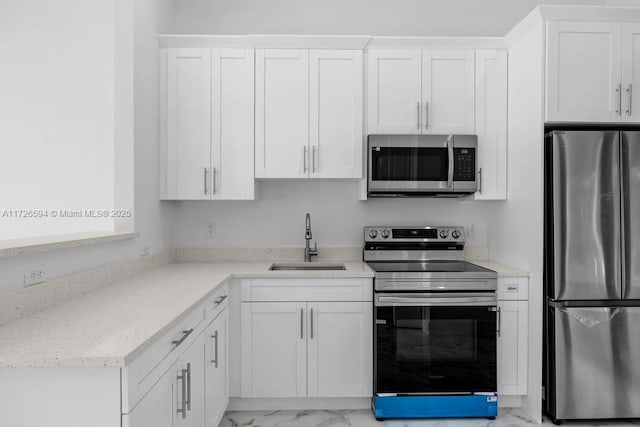 kitchen featuring stainless steel appliances, white cabinetry, sink, and light stone counters